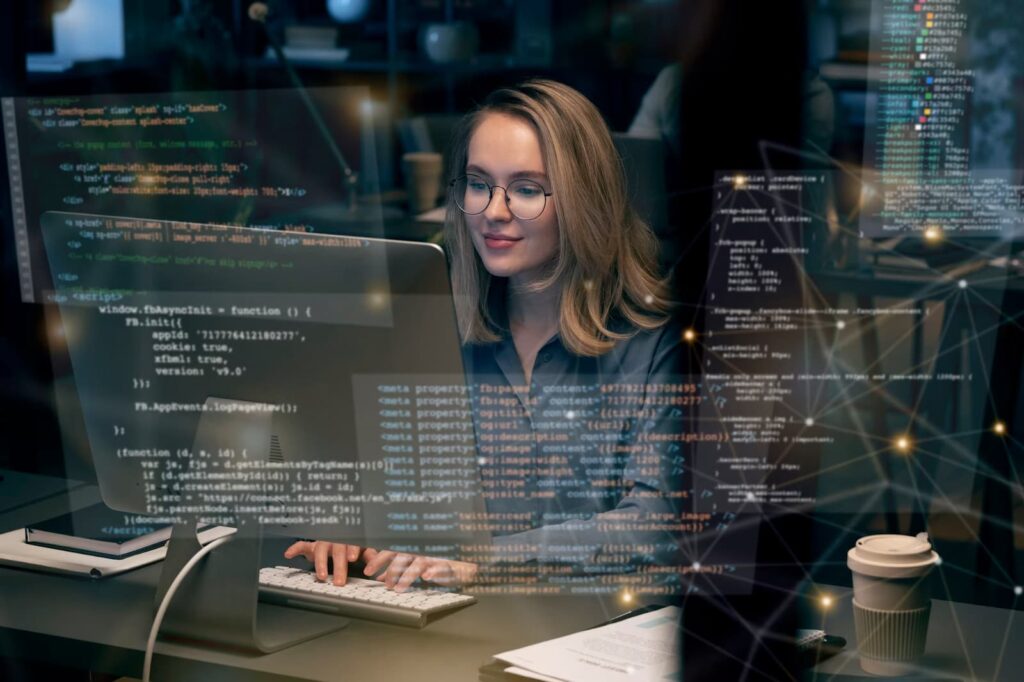 A girl works at a computer, program code is in the foreground
