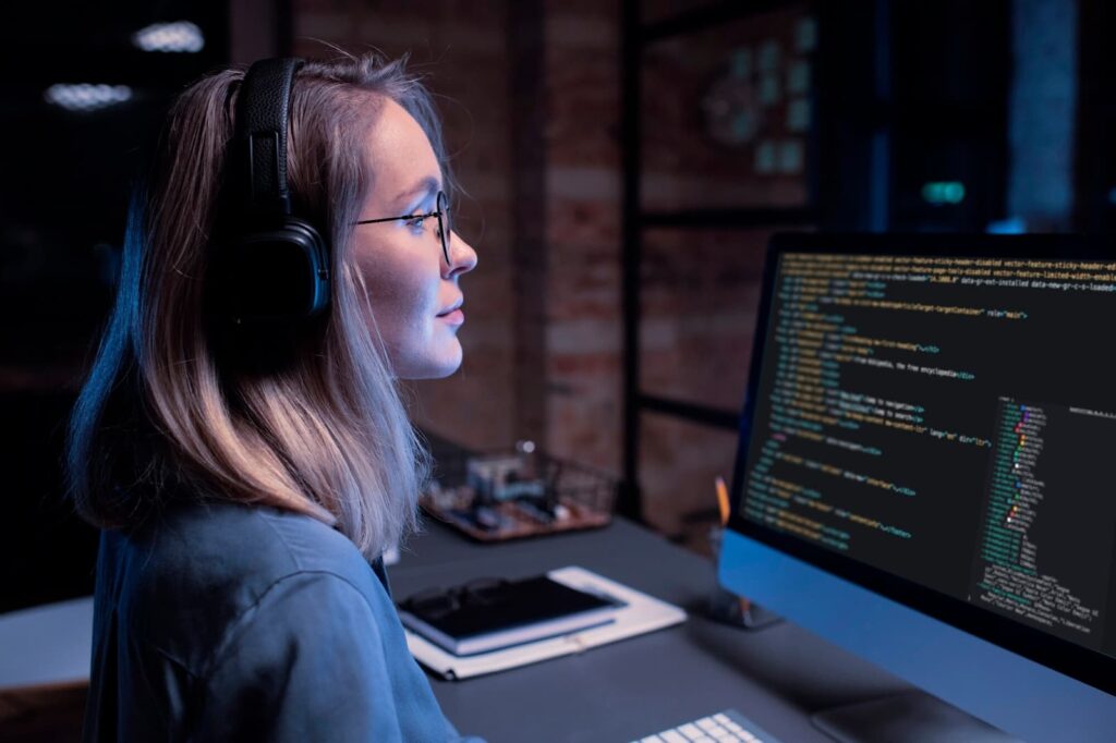 A girl in a headset works at a computer with codes